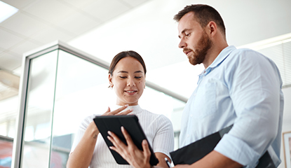 Coworkers reviewing compliance documents on a PC tablet